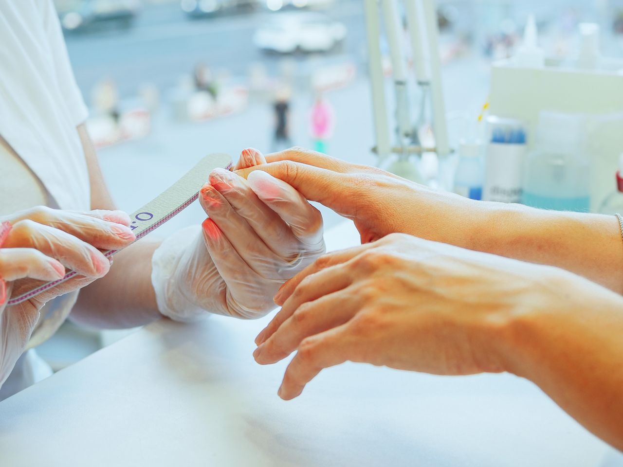 Close-up of a manicurist performing a nail file treatment on a customers hand in a salon.