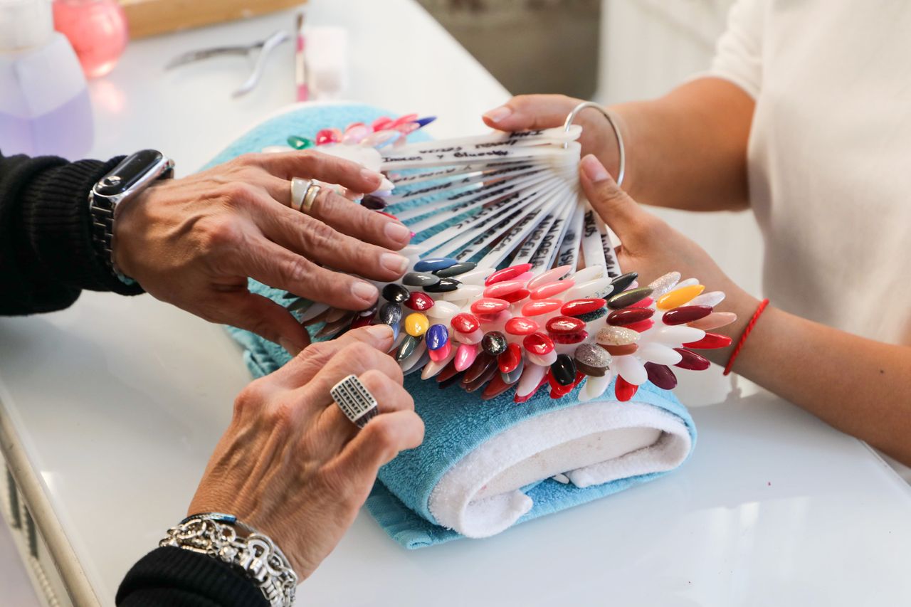 Colorful nail polish selection displayed at a salon. Hands choosing shades.